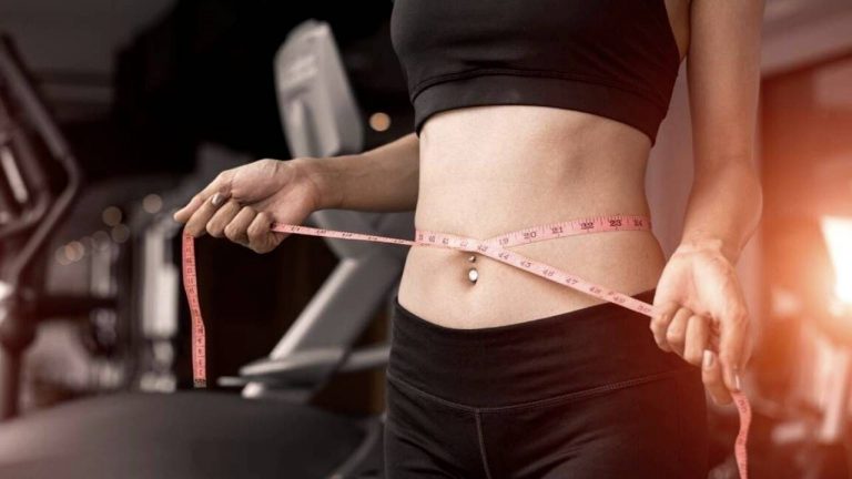 a woman with a tape meassure meassuring weight loss around her belly